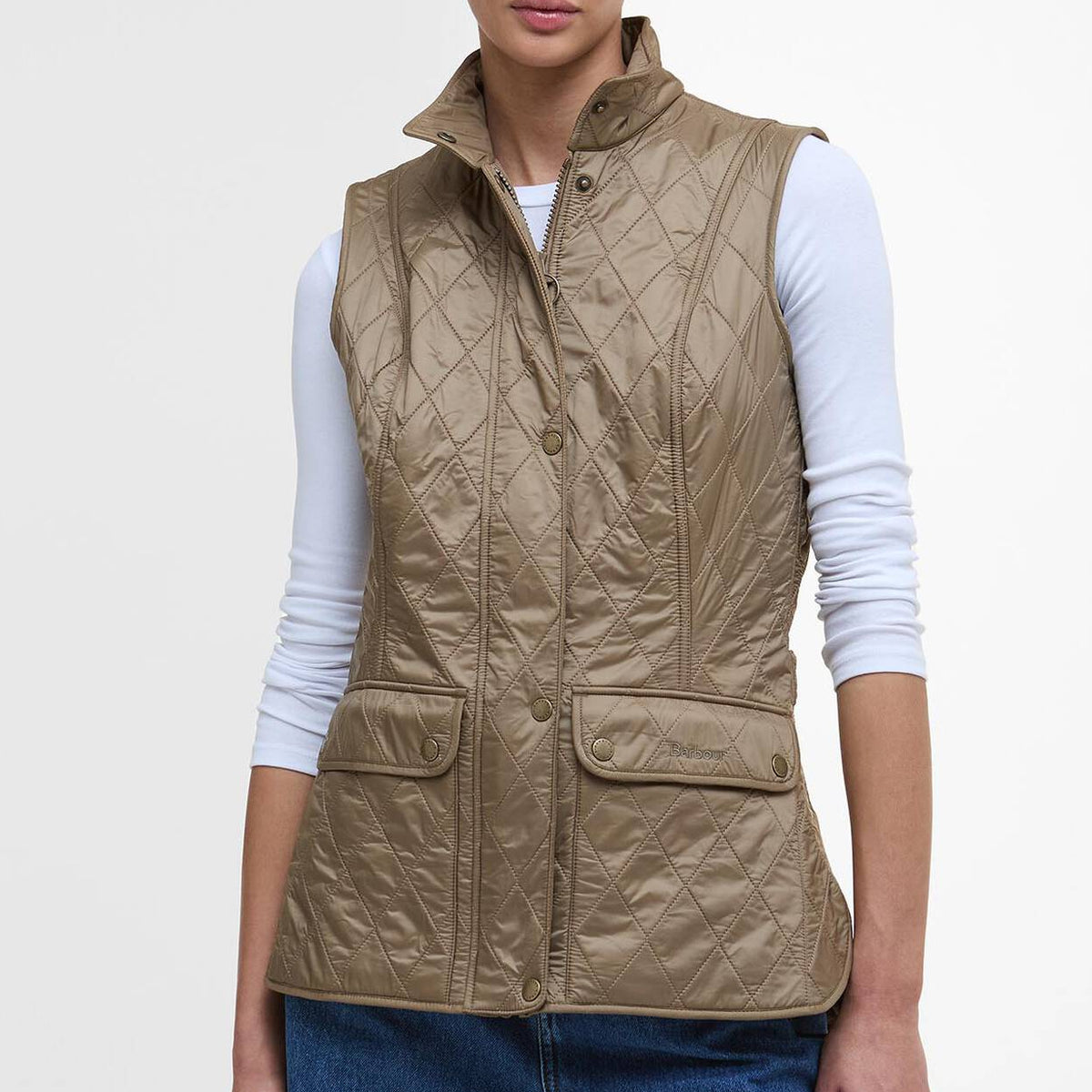 Woman wearing a Barbour beige quilted vest on a white background