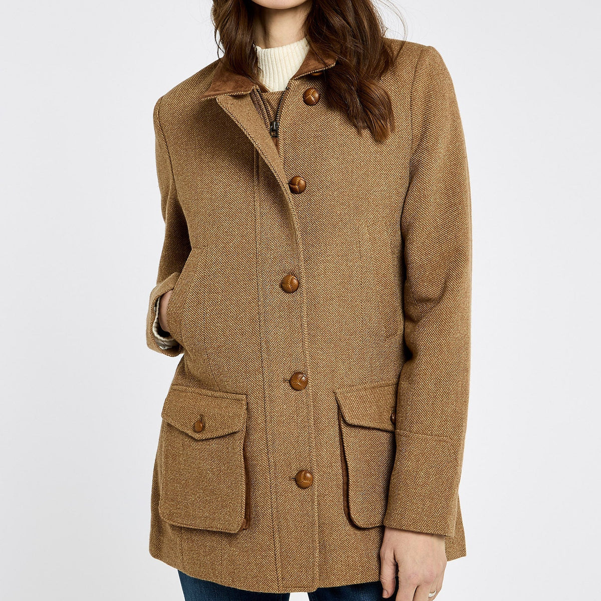 Woman wearing a brown Dubarry tweed coat with button details on a white background